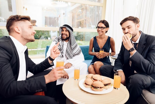 Arabi e altri uomini d'affari mangiano hamburger.