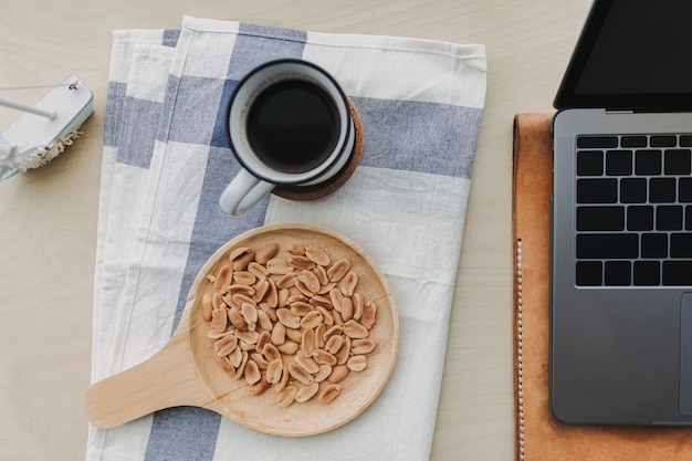 Arachidi salate caffè nero e laptop sulla scrivania