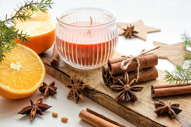 Arance fresche con anisestar, bastoncini di cannella, rami di ginepro e candela aromatica