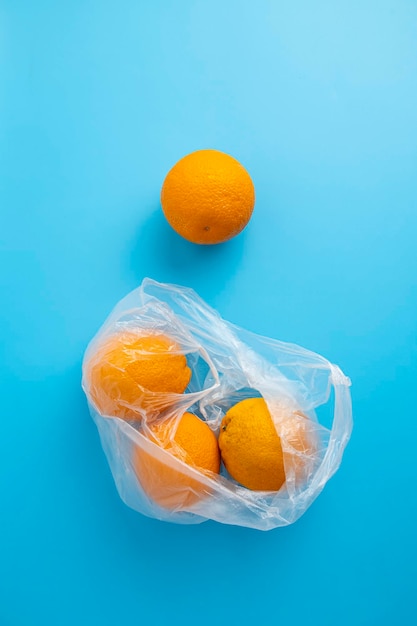 Arance fresche mature in un sacchetto di plastica trasparente su sfondo blu Vista dall'alto piatto