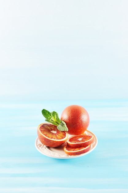 Arance rosse succose mature e fette arancio sul piatto bianco