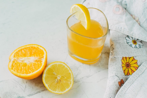Arancia succosa e un bicchiere con succo d'arancia su sfondo chiaro