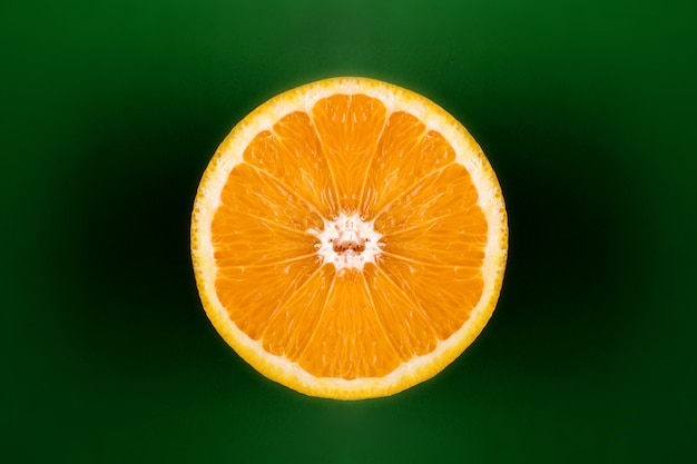 Arancia tagliata a metà su sfondo verde