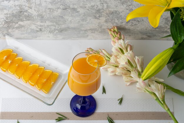 aranciata servita in un bicchiere di cristallo con una fetta e un vaso sul tavolo