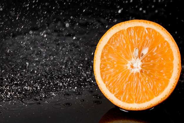 Arancione con spruzzi d'acqua sulla superficie nera