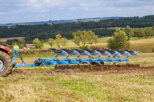 Arare il campo. Grande aratro su un trattore. Trattore con attacco agricolo.