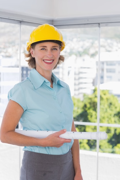 Architetto che guarda l&#39;obbiettivo con casco e cianografia