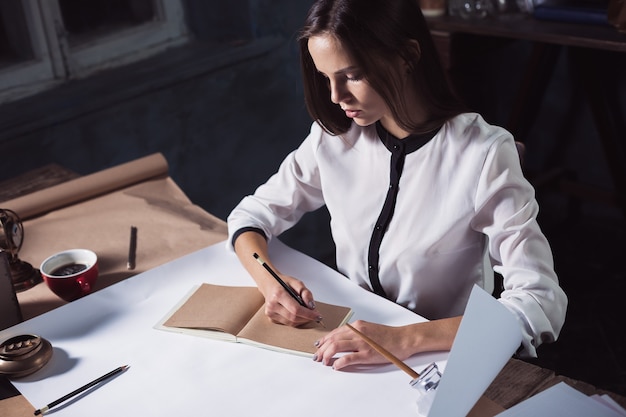 Architetto donna che lavora sul tavolo da disegno in ufficio oa casa