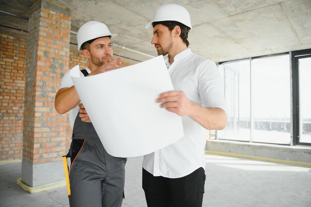 Architetto maschio che dà istruzioni al suo caposquadra al cantiere