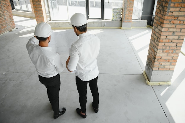 Architetto maschio che dà istruzioni al suo caposquadra al cantiere