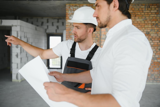 Architetto maschio che dà istruzioni al suo caposquadra al cantiere