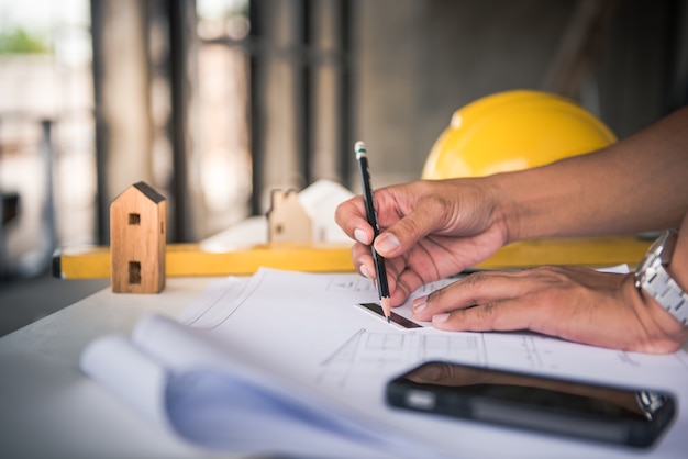 architetto uomo che lavora con le cianografie, ingegnere ispezione sul posto di lavoro per piano architettonico, schizzo