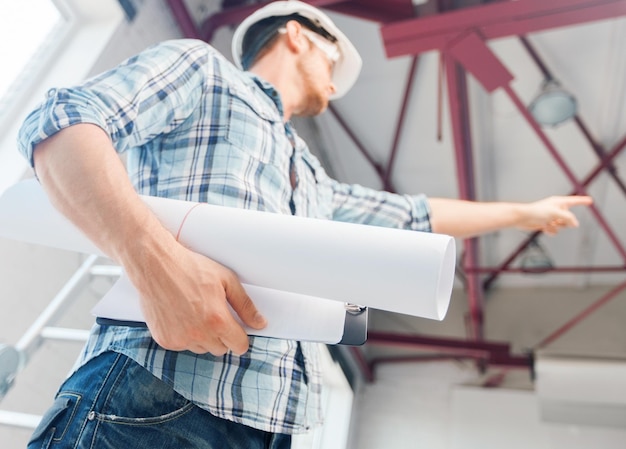 architettura e concetto di ristrutturazione della casa - uomo con casco e guanti con progetto che mostra la direzione