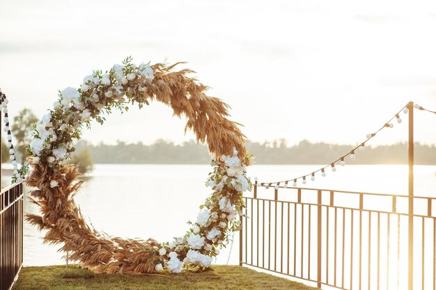 Arco a tutto sesto per una cerimonia di matrimonio in riva al fiume, sedie in vetro bianco per gli ospiti