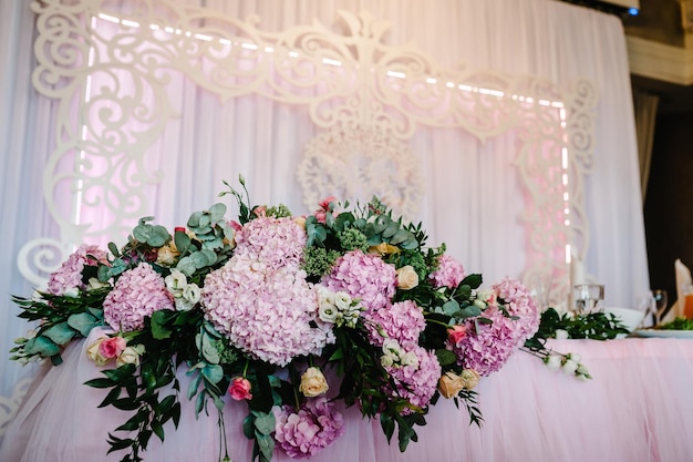 Arco da tavolo festivo decorato con composizione di fiori rosa viola viola e verde nella sala banchetti Tavolo sposi novelli nell'area banchetti sulla festa di matrimonio