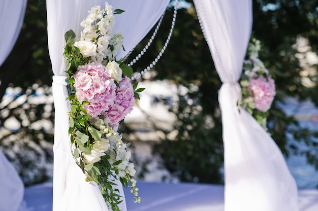 Arco di cerimonia nuziale della sposa e dello sposo decorati con i fiori delle rose.