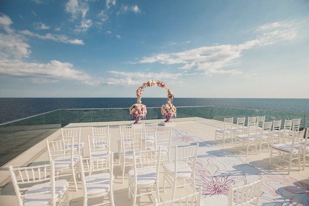 Arco di nozze con fiori freschi su uno sfondo di mare. Vasi con fiori freschi.