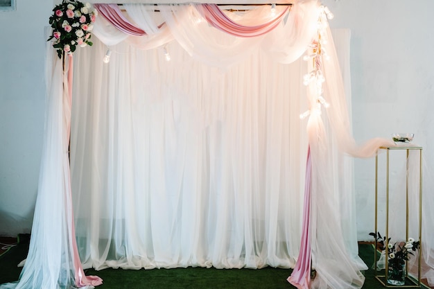 Arco festivo decorato con composizione di fiori rosa e vegetazione nella sala banchetti. Foto-muro. Concetto di buon compleanno e San Valentino.