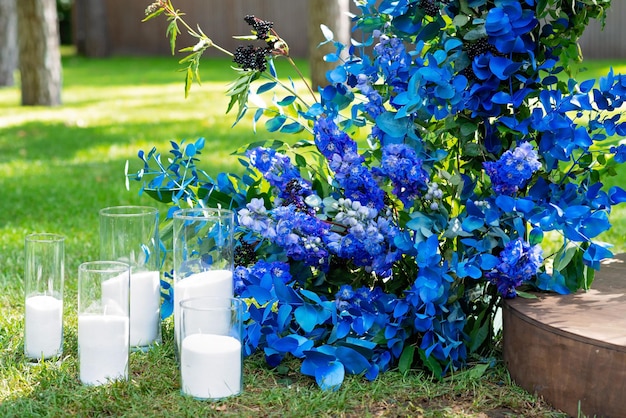 Arco per una cerimonia nuziale di fiori freschi in blu e candele, primo piano. Decorazioni per matrimoni. Messa a fuoco selettiva morbida.