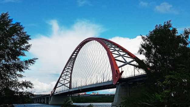 Arco rosso del ponte sospeso strallato sull'ampio fiume ob novosibirsk russia