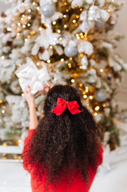 Arco rosso della ragazza castana riccia che decora il Natale