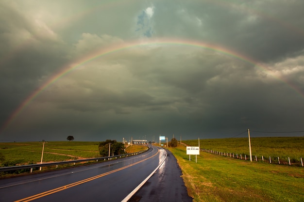 Arcobaleno dopo una tempesta in un'autostrada bagnata