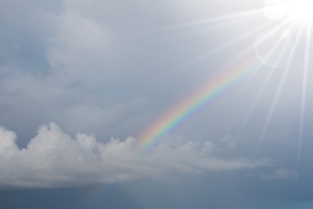 Arcobaleno nel cielo blu con bagliori di illuminazione.