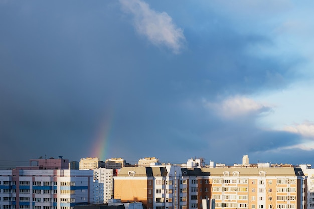 Arcobaleno nel cielo blu scuro su un'area residenziale di grattacieli sotto i raggi del sole nascente