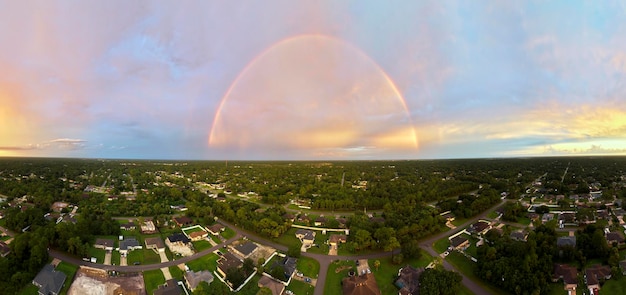 Arcobaleno rotondo colorato sopra i sobborghi della città rurale contro il cielo blu della sera dopo un forte temporale