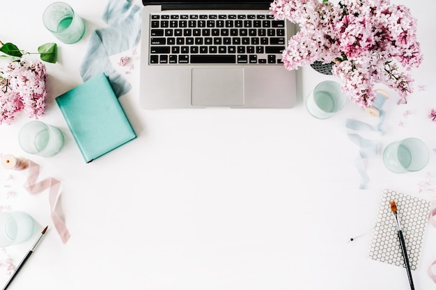 Area di lavoro con laptop, bouquet di fiori lilla e diario