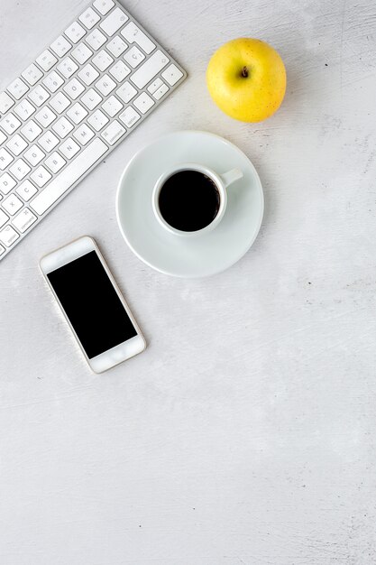 Area di lavoro con mela, tastiera, smartphone e tazza di caffè