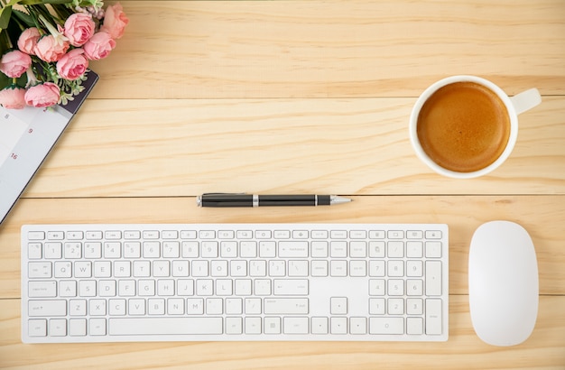 Area di lavoro con tastiera e mouse del computer bianchi e una tazza di caffè