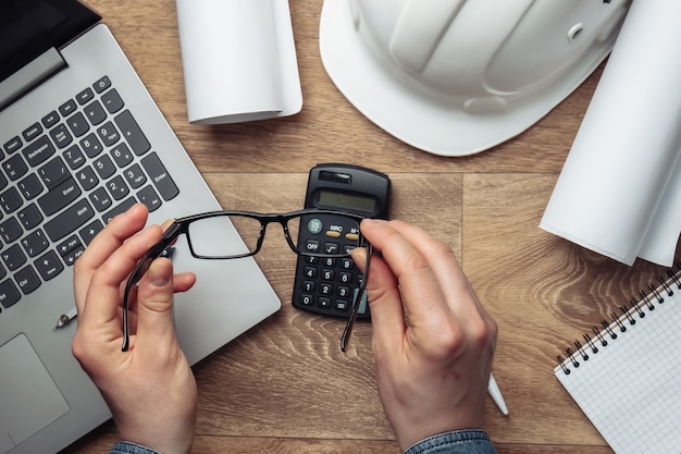 Area di lavoro dell'ingegnere. Le mani degli uomini tengono gli occhiali sul posto di lavoro.