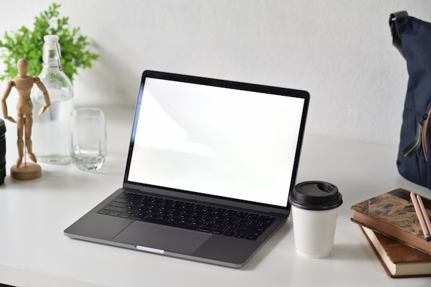 Area di lavoro di design con accessori per ufficio e laptop con schermo bianco vuoto