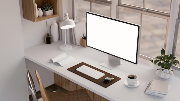 Area di lavoro moderna della scrivania dell'ufficio con il modello bianco del computer desktop del PC sul tavolo bianco