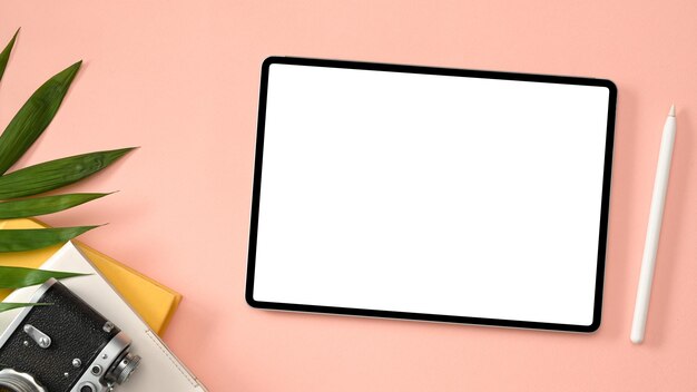 Area di lavoro per blogger di viaggio con fotocamera con penna stilo mockup per tablet e accessori su sfondo rosa