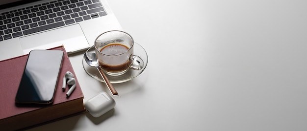 Area di lavoro semplice con copia spazio, laptop, tazza di caffè, libro, smartphone e auricolare wireless