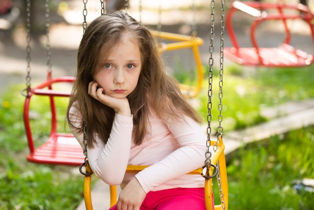 Area giochi Bambino oscillante Donna esausta annoiata nel parco Bella giornata per una bambina carina nel parco