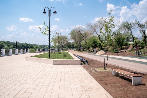 Argine degli Urali Estate La trama dell'argine della città con una panchina e un parcheggio per biciclette