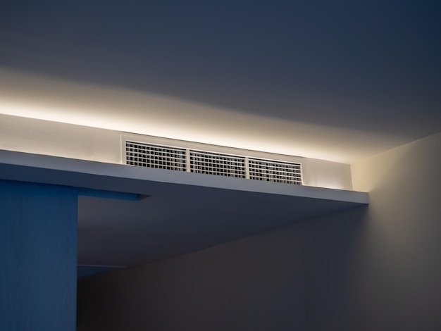 Aria condizionata sistema di ventilazione a parete sul soffitto nella stanza d'albergo bianca con luce debole griglia di ventilazione dell'aria della stanza d'Albergo sulla parete