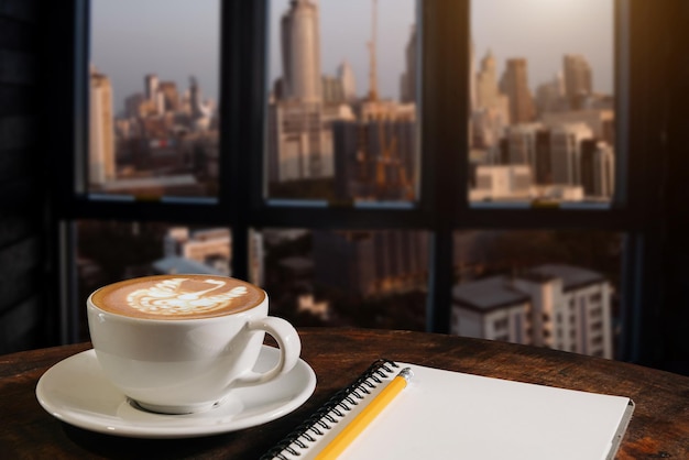 Aroma di caffè in tazza colazione bevanda mattutina sul tavolo di legno nel negozio di caffè con blocco note e sfondo di giornale