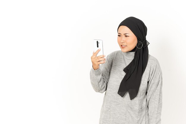 Arrabbiato per la videochiamata di una bella donna asiatica che indossa l'hijab isolato su sfondo bianco