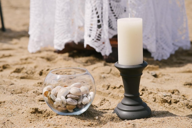 Arredamento di una cena romantica in riva al mare o all'oceano Una candela su un candeliere e pietre di mare in un vaso di vetro