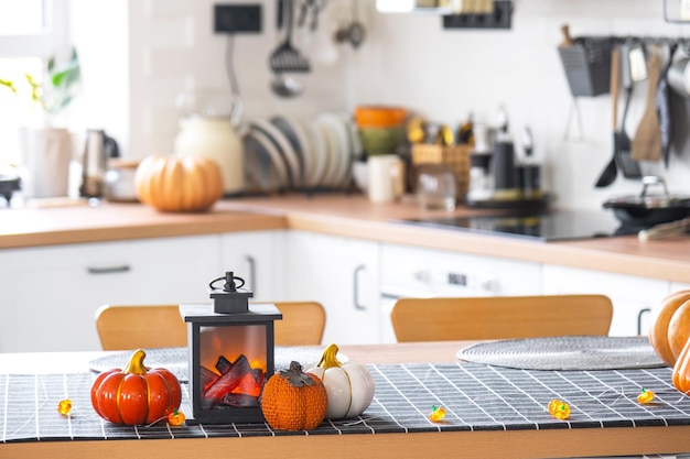 Arredamento di una cucina classica bianca con ghirlande di zucche in lanterna per Halloween e raccolto con statuetta di casa Atmosfera autunnale in un interno di casa moderno in stile loft, mutuo assicurativo immobiliare