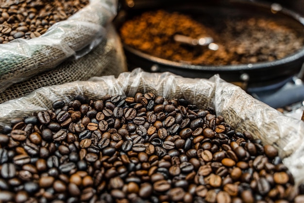 Arrostire i chicchi di caffè di robusta e arabica nel mercato turco cesto di legno. Diversi gradi di torrefazione del caffè.