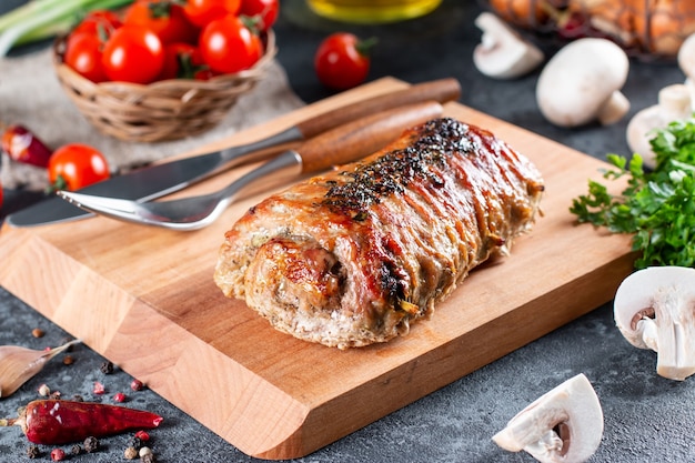 Arrosto di maiale ripieno di funghi e formaggio su una tavola di legno