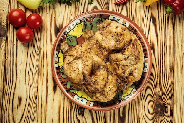 Arrosto di pollo fritto caldo alla griglia Tabaka con erbe aromatiche e aglio su fondo di legno
