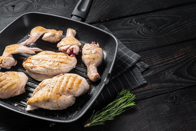 Arrosto su una padella alla griglia pollo carne e parti di pollo coscia filetto di petto ala coscia Sfondo di legno nero Vista dall'alto Spazio di copia