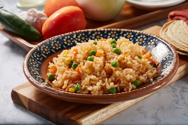 Arroz a la jardinera rojo con zanahoria chicharos y elote servido en plato mexicano