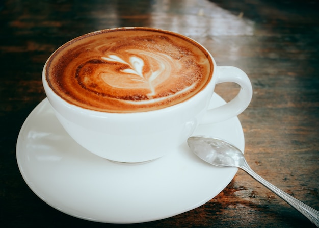 Arte calda del latte del caffè sulla fine di legno del fondo della tavola su